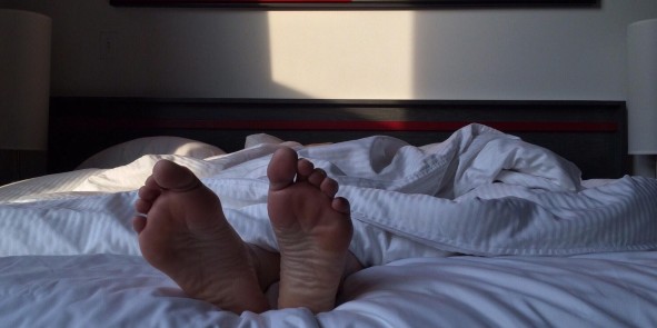 Füße schauen unter Bettdecke hervor 