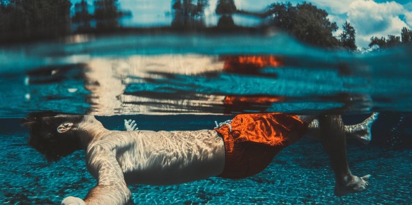 Junger Mann der auf dem Rücken schwimmt